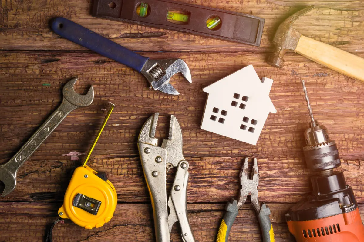 Assortment of random tools on a table with a metal cutout of a house